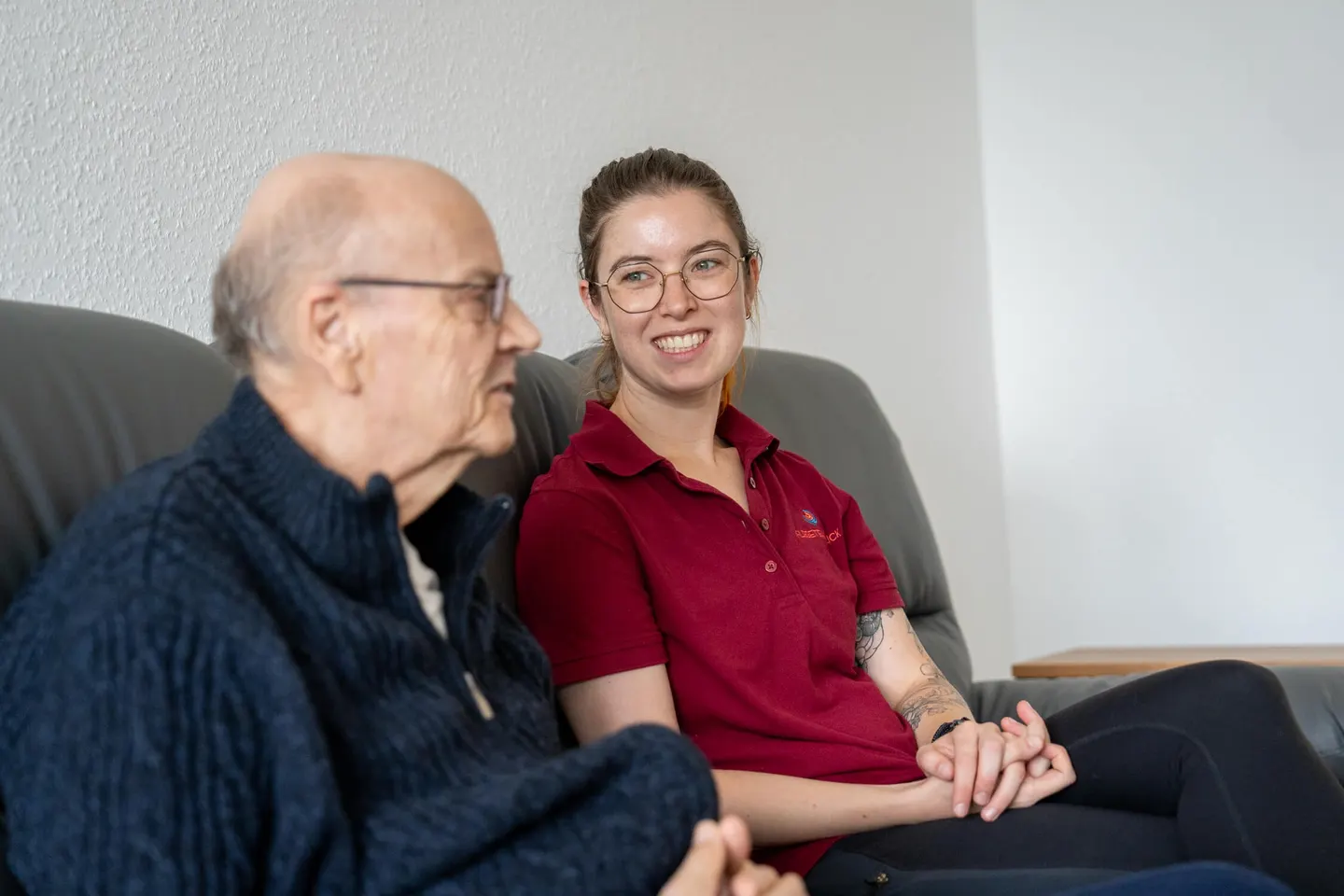 Bewohner und Cardia-Mitarbeiterin sitzen zusammen im Wohnzimmer der Springbachhöfe